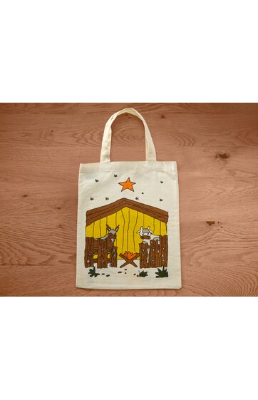 Beige Stofftasche mit Motiv einer Krippe in Braun und Gelb, brauner, gezackter Zaun, brauner Esel links, weißes Schaf rechts, oranges Lagerfeuer in der Mitte, großer orangefarbener Stern oben, kleine schwarze Sterne verteilt