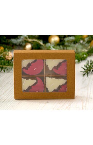 Braune Geschenkbox mit durchsichtigem Fenster, innen vier runde Schokoladen mit Weihnachtsbaum- und Halbmondmotiv, Schokoladen in Weiß und Dunkelrot, Box liegt auf hellen Holzdielen, Tannenzweige und Weihnachtskugeln im Hintergrund