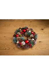 Weihnachtskranz aus Tannenzapfen, grünen Tannenzweigen, roten Kugeln und roten Beeren, verziert mit kleinen weißen Sternen, rund, auf hellem Holztisch liegend