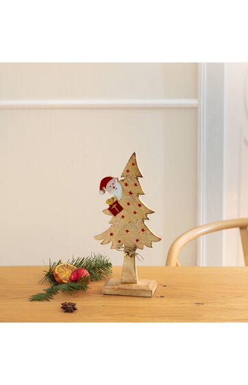 Weihnachtsbaumskulptur aus Holz, hellbraun mit roten Sternen, Weihnachtsmannfigur an der Seite, auf rechteckigem Sockel stehend, Dekoration auf Holztisch mit Tannenzweig, Nuss und roter Kugel daneben