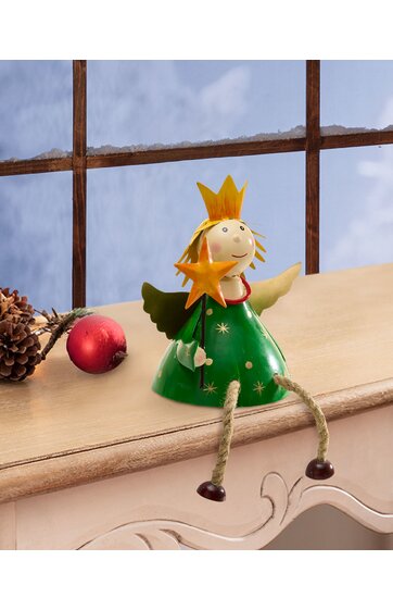 Figur eines grünen Engels mit goldener Krone und Stern in der Hand, sitzt mit ausgebreiteten Armen auf einer cremefarbenen Fensterbank, beine aus Seil mit braunen Holzfüßen, roter Christbaumschmuck und Kiefernzapfen daneben
