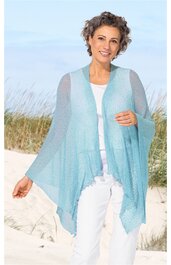 Hellblaue, transparente Strickweste ohne Verschluss, asymmetrischer Saum, getragen von lächelnder, stehender Frau mit weißem Oberteil und weißer Hose am Strand