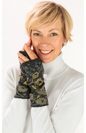 Fingerlose Handschuhe dunkelgrün mit floralem Muster, schwarze Saumkanten, getragen von lächelnder stehender Frau in weißem Rollkragenpullover, eng anliegend, Daumenöffnung