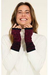 Paar handgestrickte pulswärmer in dunkelrot mit schwarzem Spitzenmuster, über die Handgelenke gezogen, getragen von lächelnder Frau in weißem Langarmshirt, fingerlose Handschuhe ohne Daumenöffnung