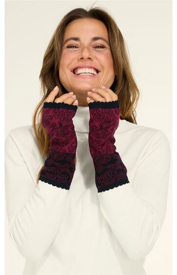 Paar handgestrickte pulswärmer in dunkelrot mit schwarzem Spitzenmuster, über die Handgelenke gezogen, getragen von lächelnder Frau in weißem Langarmshirt, fingerlose Handschuhe ohne Daumenöffnung