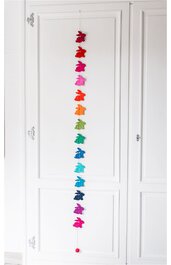 Langer Hängeschmuck mit 14 Hasenfiguren in verschiedenen Farben, von oben nach unten in Rot-, Pink-, Orange-, Grün-, Blau- und Lilatönen, verbunden durch Schnur, an weißer Schranktür hängend