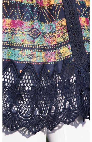 Multifarbiger Stoff mit abstraktem Muster in Gelb, Pink, Blau und Grün, angrenzend an schwarzen Häkelspitzenbesatz mit floralem Muster und scalloped Kante