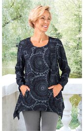 Langärmliges Tunika-Shirt in dunklem Blau mit hellblauem, rundem Mandalamuster, Rundhalsausschnitt, spitz zulaufender Saum, zwei Taschen vorne, getragen von lächelnder stehender Frau