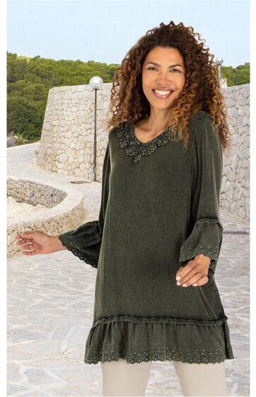 Dunkelgrüne Tunika mit Rüschensaum und Spitzenbesatz am Saum und am V-Ausschnitt, lange Ärmel mit Volant, getragen von lächelnder Frau mit lockigen Haaren, locker geschnitten