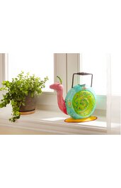 Dekorativer Wasserkessel in Form einer Schnecke, türkisfarben mit grüner Schneckenhauszeichnung und roten Armen, mit schwarzem Griff, auf gelbem Untersetzer stehend auf Fensterbrett neben grünem Topfpflanze mit kleinen Blättern