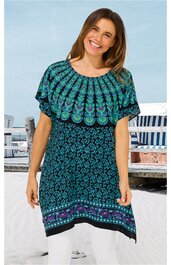 Kurzärmeliges Kleid mit rundem Ausschnitt, dunkelblau mit türkisfarbenem und lila Blumenmuster, breite Musterbordüren am Ausschnitt und Saum, gerade geschnitten, getragen von lächelnder stehender Frau