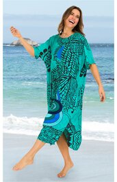 Türkisgrünes Strandkleid mit schwarzem und blauem abstraktem Muster, halblange weite Ärmel, knielang, leger geschnitten, getragen von lächelnder stehender Frau am Strand