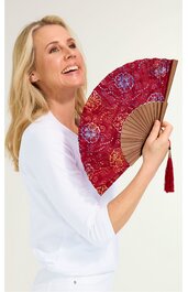 Handfächer dunkelrot mit goldfarbenen und blauen Blumenmustern, Holzstiele, roter Quast am Griff, gehalten von stehender lächelnder Frau in weißem Oberteil