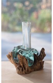 Klarglasvase mit hohem, schmalem Hals, umgeben von transparent grünem, unregelmäßig geformtem Glas, montiert auf unregelmäßig geformtem braunem Treibholzfuß, steht auf hellem Untergrund