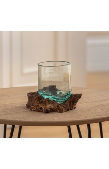 Trinkglas klar mit leicht grünem Stich, rund, auf brauner Holzunterlage mit unregelmäßiger, naturnaher Form, ohne Henkel, auf rundem Holztisch