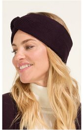 Schwarzes Stirnband mit gedrehtem Knoten vorne, getragen von lächelnder Frau mit langen blonden Haaren und weißem Rollkragenpullover