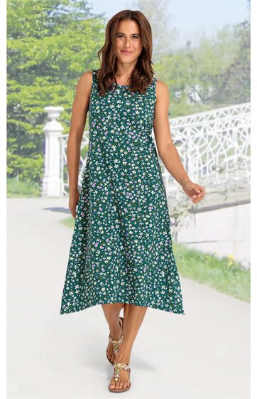 Ärmelloses Midikleid in grün mit weißem Blumenmuster, rundem Ausschnitt, ausgestellter Rock, getragen von stehender Frau, knieumspielende Länge