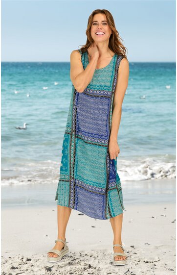 Ärmelloses, knöchellanges Sommerkleid in Türkis und Blau mit geometrischem Muster, rundem Ausschnitt, lockerer Schnitt, getragen von lächelnder Frau am Strand, mit Sandalen
