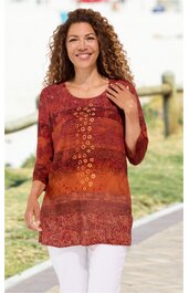 Rostrotes Langarmshirt mit verschiedenfarbigen Mustern, Rundhalsausschnitt, mittellang, mit bronzefarbenen Ösen in vertikaler Anordnung vorne, getragen von stehendem, lächelndem Model, weiße Hose