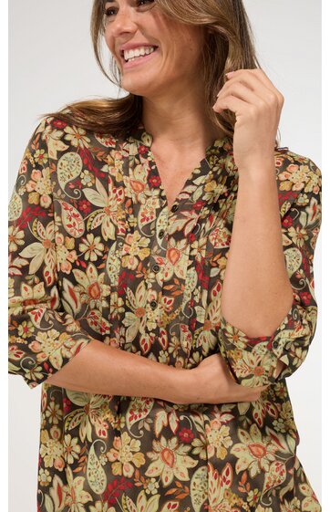 Damenbluse in dunkelgrün mit buntem Blumenmuster, V-Ausschnitt mit kleiner Knopfleiste, lange Ärmel, lockere Passform, getragen von stehender Frau mit hochgezogenen Ärmeln
