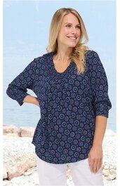 Marineblaue Bluse mit runden Mustern in Hellblau und Violett, V-Ausschnitt mit kleinem Stehkragen, lange Ärmel mit Bündchen, lockere Passform, getragen von stehender lächelnder Frau vor hellem Hintergrund