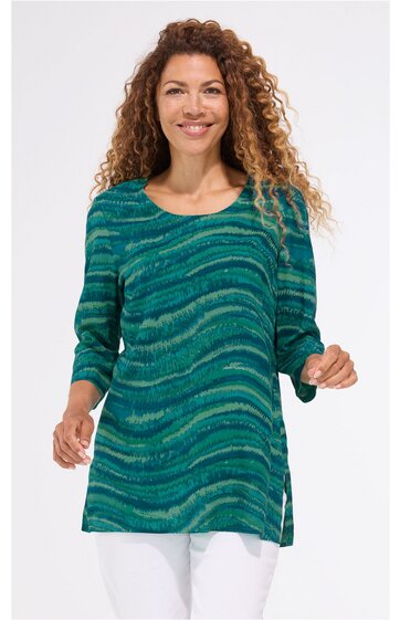 Grün-blau gemustertes Tunikaoberteil mit wellenförmigem Design, Rundhalsausschnitt, dreiviertellangen Ärmeln, seitlichen Schlitzen, getragen von stehender Frau