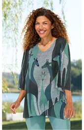 Langärmeliges Damenoberteil in verschiedenen Grüntönen und Grau, mit abstraktem Giraffenmuster, asymmetrischer Saum, V-Ausschnitt, getragen von stehender lächelnder Frau