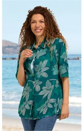 Grüne Bluse mit großen weißen Blütenmustern, Hemdblusenkragen, halblange Ärmel, längs geschnitten, getragen von lächelnder Frau stehend am Strand