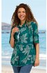Grüne Bluse mit großen weißen Blütenmustern, Hemdblusenkragen, halblange Ärmel, längs geschnitten, getragen von lächelnder Frau stehend am Strand