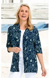 Damenstrickjacke, dunkelblau mit hellblauem floralen Muster, offene Vorderseite ohne Knöpfe, Dreiviertelärmel, locker geschnitten, getragen von lächelnder stehender Frau