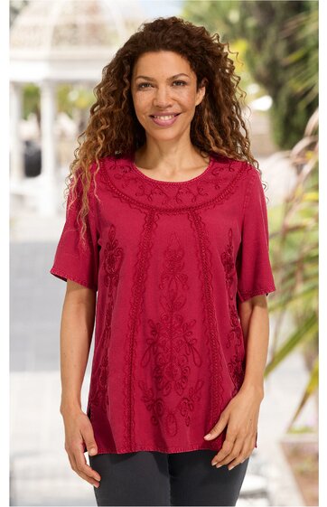 Rotes Kurzarmshirt mit floralem Muster vorne, Rundhalsausschnitt, locker geschnitten, getragen von stehender Frau mit lockigen Haaren