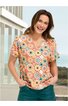 Bunte Damenbluse in Orange mit Blumen- und Kreismuster, V-Ausschnitt, kurze Ärmel, locker sitzend, getragen von lächelnder stehender Frau mit Händen in den Hosentaschen
