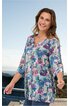 Tunika für Damen, mehrfarbig mit floralem Muster in Blau-, Rosa- und Grüntönen, langer Schnitt, Knopfleiste am Ausschnitt, 3/4-Ärmel, getragen von stehender lächelnder Frau