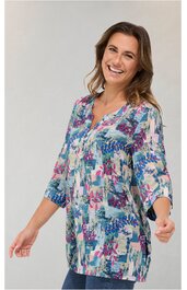 Lange Bluse in hellgrau mit abstraktem Muster in Pink, Blau und Türkis, halblange Ärmel mit Bündchen, V-Ausschnitt mit Schlitz und Knopfleiste, locker geschnitten, getragen von lächelnder Frau in stehender Pose
