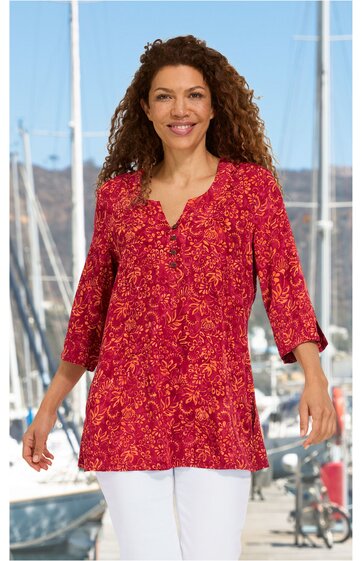 Rotes Longshirt mit orangem Blumenmuster, V-Ausschnitt, Drei-Viertel-Ärmel, gerade geschnitten, getragen von lächelnder stehender Frau vor Hafen mit Segelbooten