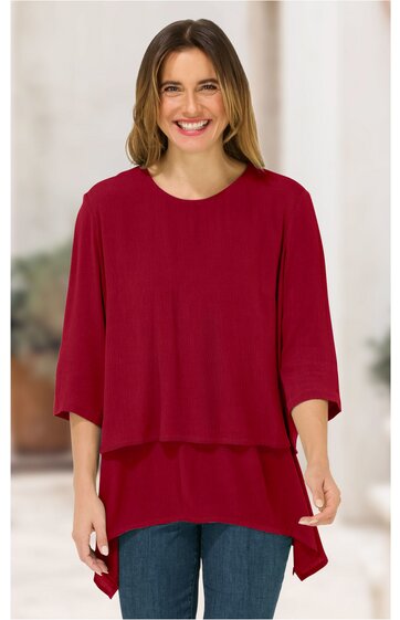 Rotes Oberteil mit zweilagigem Design, locker sitzend, Rundhalsausschnitt, halblange Ärmel, asymmetrischer Saum, getragen von stehender Frau, gerade geschnitten