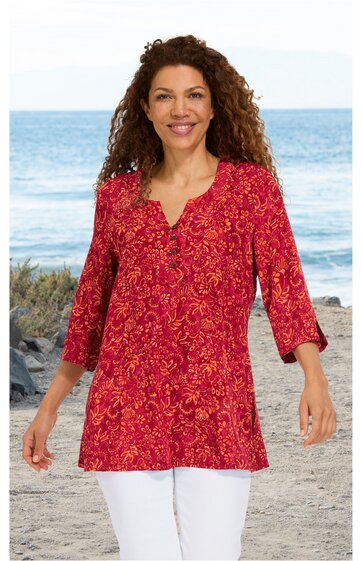 Rotes Langarmshirt mit gelbem Blumenmuster, V-Ausschnitt mit Knopfleiste, locker geschnitten, getragen von lächelnder Frau im Stehen am Strand