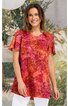 Rotes T-Shirt mit orangenen und pinken Spiralmustern, Rundhalsausschnitt, kurze Ärmel, gerade geschnitten, getragen von lächelnder Frau im Stehen
