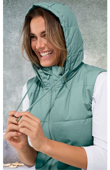 Ärmellose gesteppte Weste in mintgrün mit Stehkragen, Kapuze mit Kordelzug, seitlichen Eingrifftaschen, getragen von lächelnder, stehender Frau mit weißen Dreiviertelärmeln