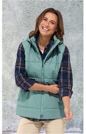 Ärmellose, hellgrüne Weste mit Stehkragen, durchgehendem Reißverschluss, zwei seitlichen Eingrifftaschen, getragen von lächelnder Frau in kariertem, blau-weißem Hemd und beiger Hose, stehende Pose