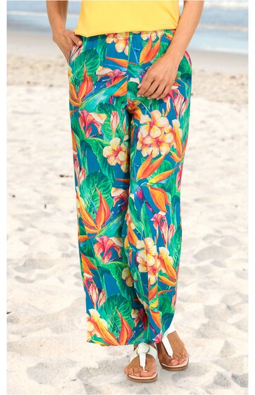 Weite lange Hose in Türkis mit buntem tropischem Blumen- und Blattmuster, elastischer Bund, seitliche Eingrifftaschen, getragen von stehender Person