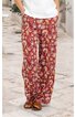 Weite lange Hose in rot mit gelbem und grünem Blumenmuster, gerader Schnitt, getragen von stehender Person, elastischer Bund, Taschen an den Seiten