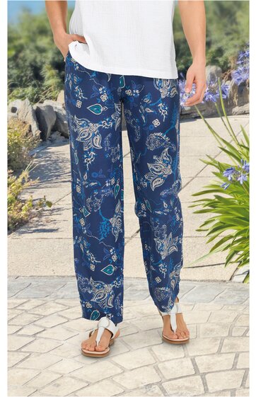 Locker sitzende, dunkelblaue Freizeithose mit abstraktem weißen und hellblauen Muster, elastischer Bund, gerade geschnitten, getragen von stehender Person mit weißen Sandalen und weißem T-Shirt