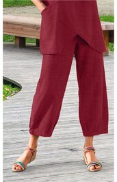 Rote weite Hose mit elastischem Saum am Beinabschluss, zwei seitliche Taschen, getragen von stehender Person, kombiniert mit bunten Sandalen mit Riemchen