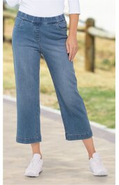 Helle Jeanshose mit weitem Bein, mittelhoch tailliert, elastischer Bund ohne Verschluss, hüftlang, getragen von stehender Person mit weißem Oberteil und weißen Sneakers