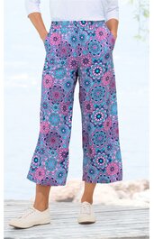 Weite Hose in Lila mit blauem und rosa floralem Muster, hoher Bund mit Hosentaschen, 7/8-Länge, getragen von stehender Person, lockerer Schnitt