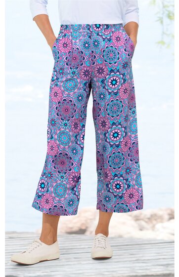 Weite Hose in Lila mit blauem und rosa floralem Muster, hoher Bund mit Hosentaschen, 7/8-Länge, getragen von stehender Person, lockerer Schnitt