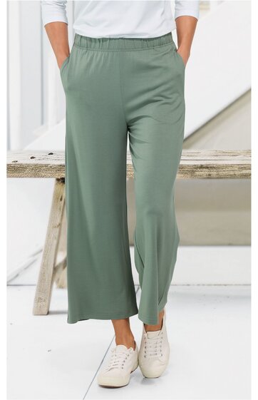 Hose in salbeigrün, weit geschnitten, elastischer Bund, glatter Stoff, getragen von stehender Person von vorne, kombiniert mit weißen Sneakern und weißem Oberteil