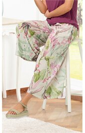 Hose in hellgrün mit floralem Muster in Rosatönen und Grün, weit geschnitten, knöchellang, getragen von sitzender Person, elastischer Bund, locker fallend