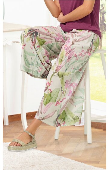 Hose in hellgrün mit floralem Muster in Rosatönen und Grün, weit geschnitten, knöchellang, getragen von sitzender Person, elastischer Bund, locker fallend